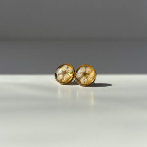 sztyfty z białym kwiatem na złotym tle